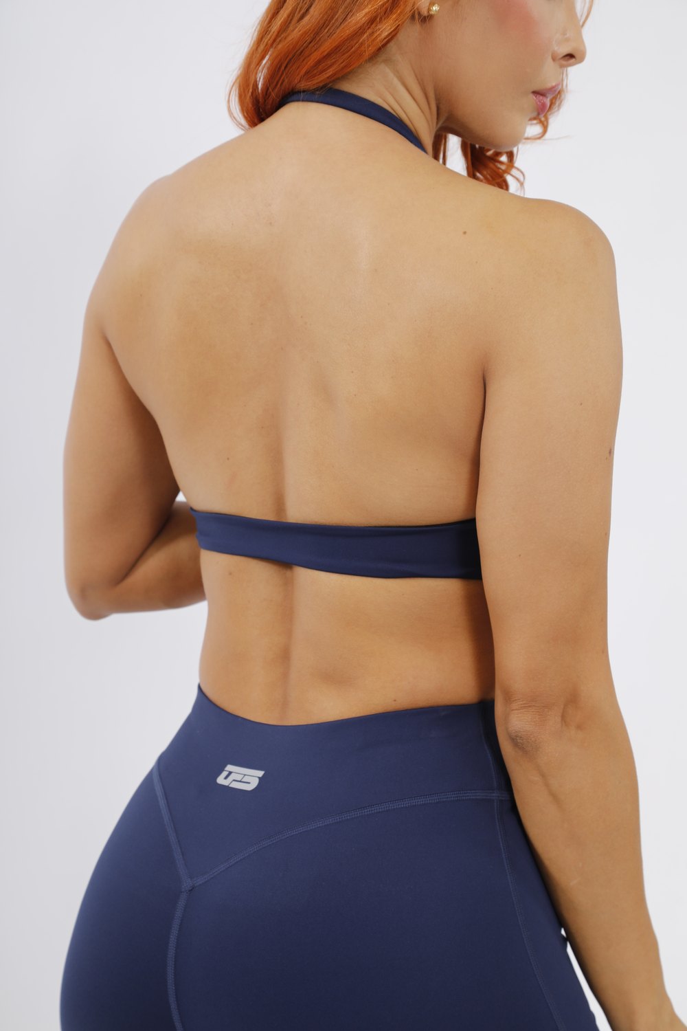 Espalda de mujer con top y leggins azul navy UFSport